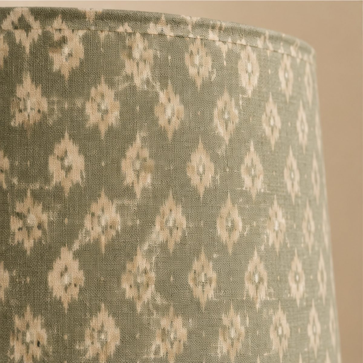 Contact Close-up of the green ikat fabric of a table lamp shade, showing the weave and the pattern